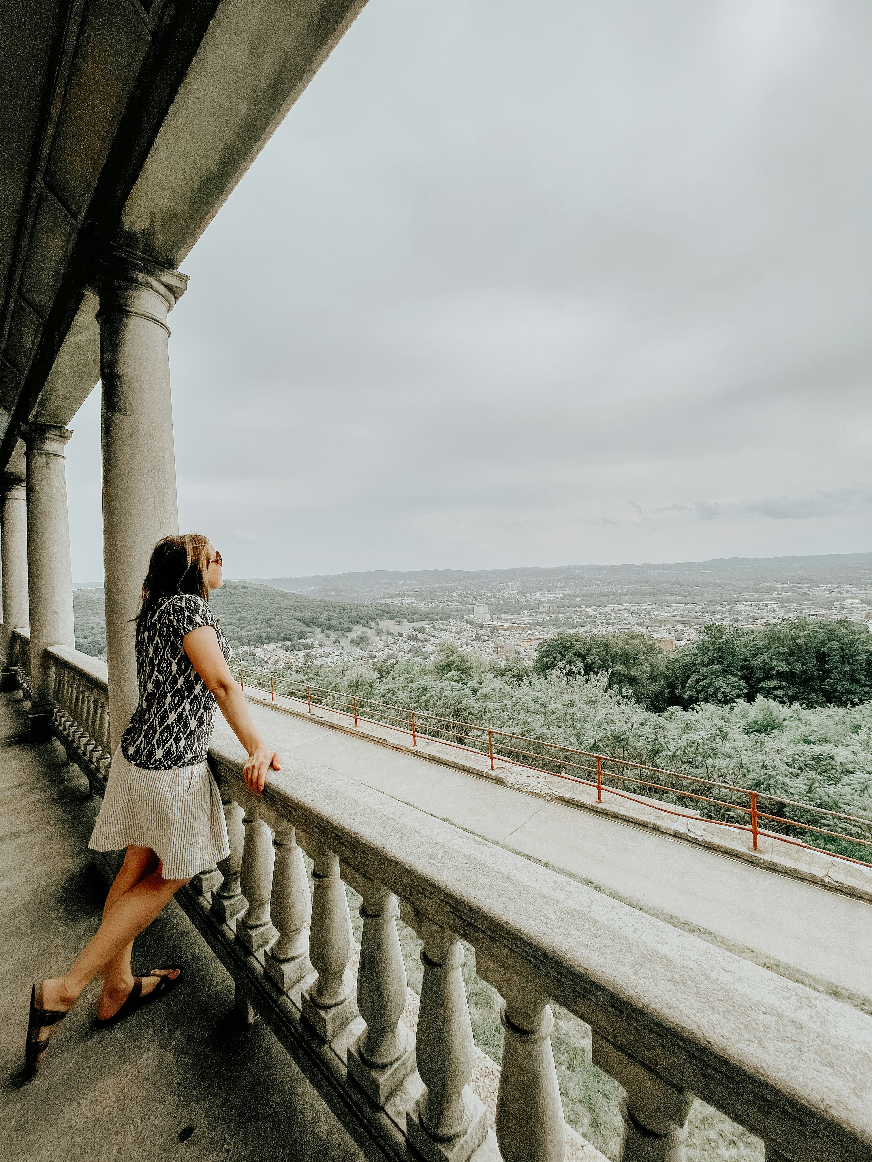 woman in black and white dress standing on gray concrete bridge during daytime