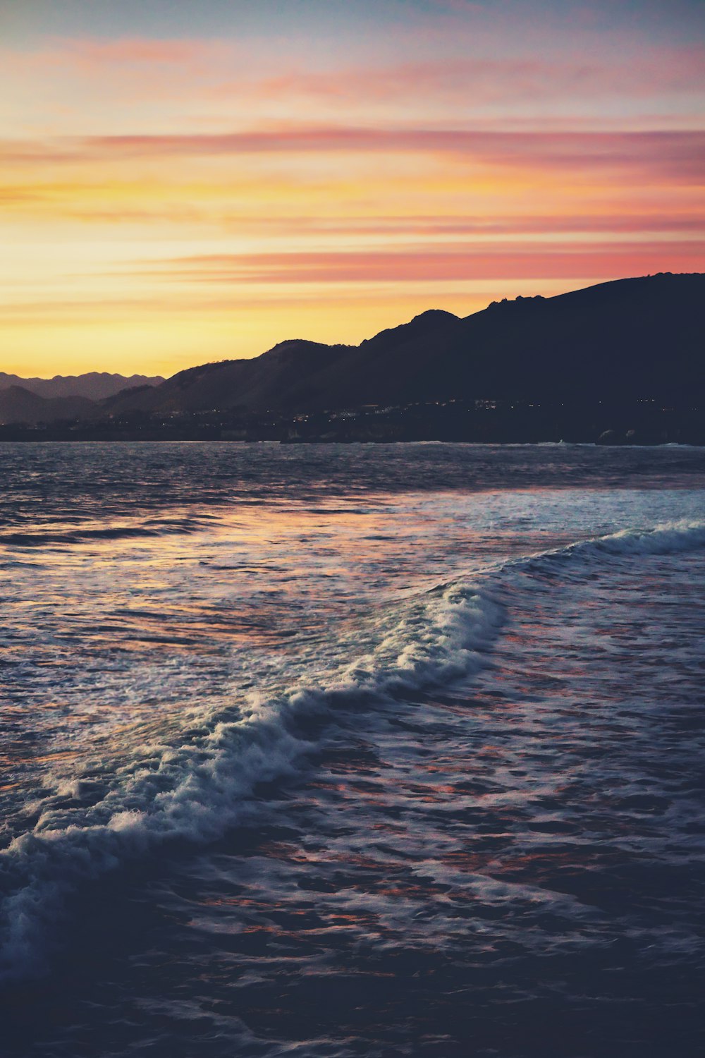 Olas del océano rompiendo en la costa durante la puesta de sol