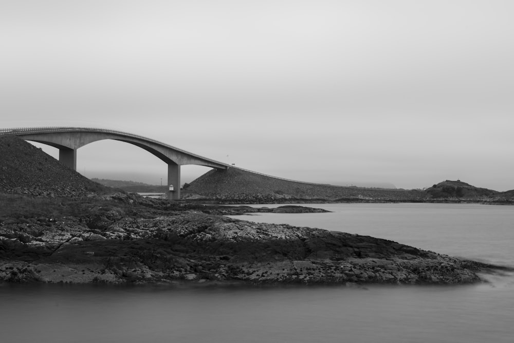 grayscale photo of bridge over the sea