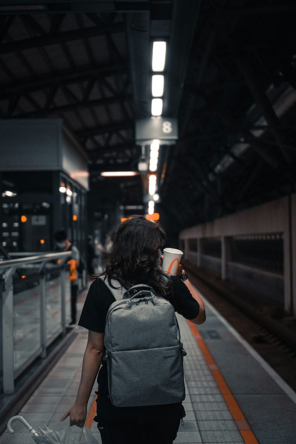 woman in black jacket and gray backpack standing on train station