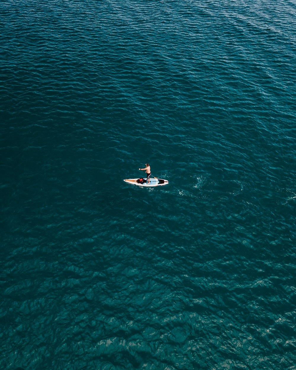 man riding white surfboard on body of water during daytime