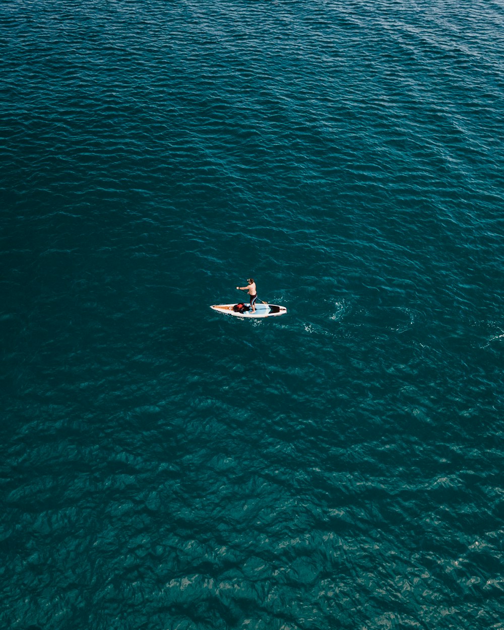 homem que monta prancha de surf branca no corpo de água durante o dia
