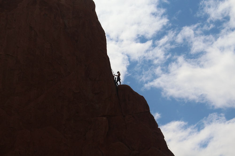 person climbing on brown rock mountain during daytime