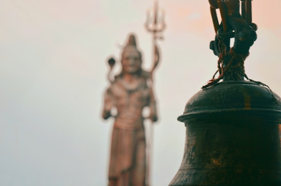 black bell with three human statues