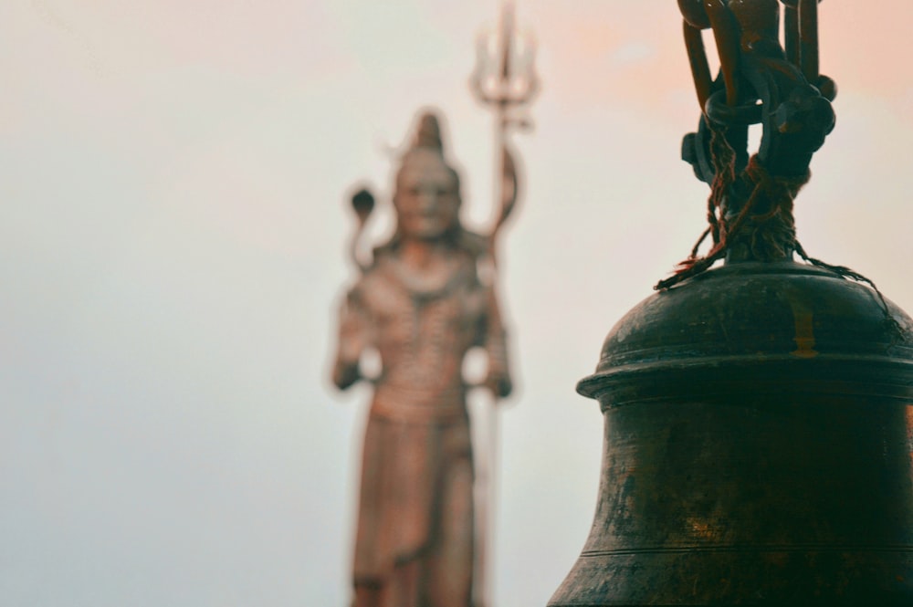 black bell with three human statues