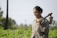 A smiling woman proudly standing in her thriving vegetable garden in rural Nigeria.