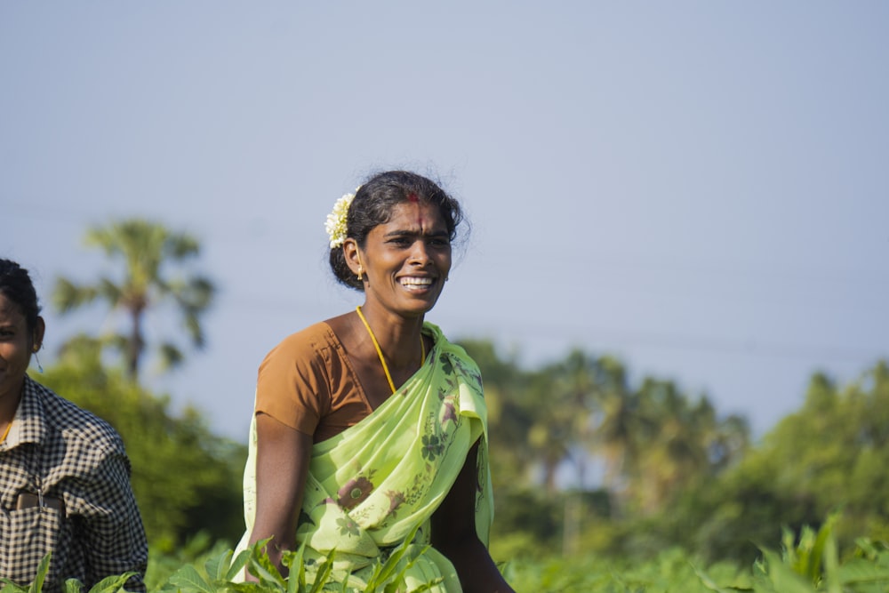 woman in green and yellow sari standing on green grass field during daytime