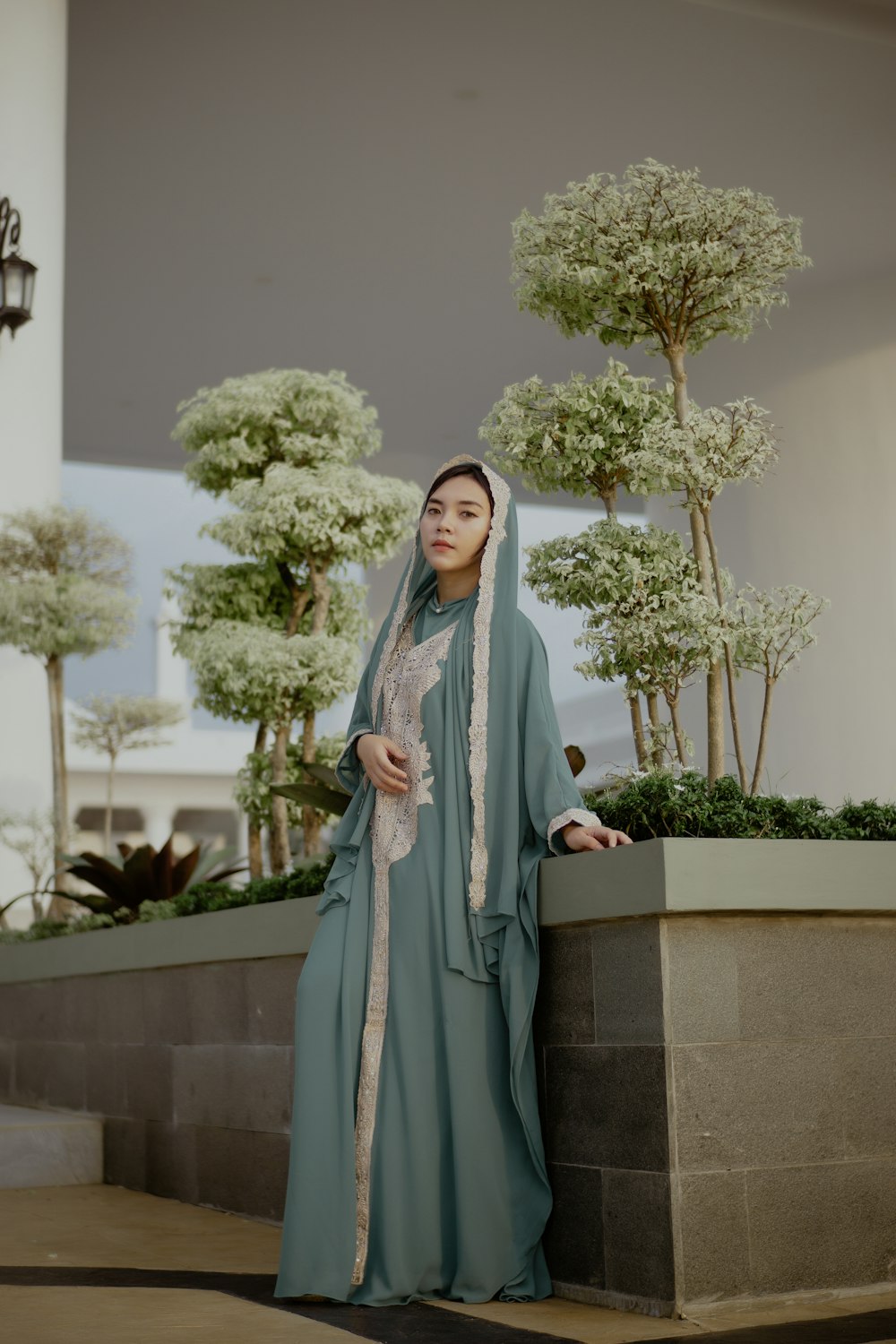 Mujer con hiyab gris de pie cerca de una planta verde durante el día