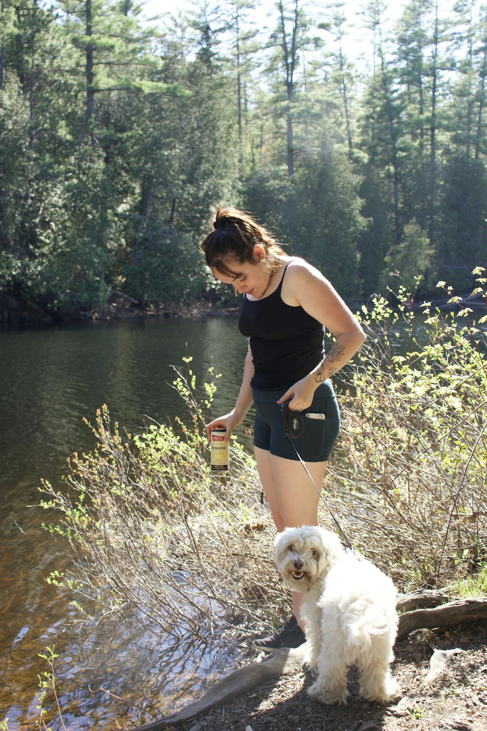 woman in black tank top and black shorts holding green can standing on green grass field