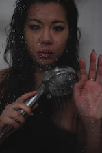 Hands installing a water-saving shower aerator under a modern bathroom showerhead.