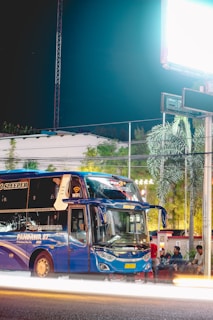 A 74-seater luxury coach illuminated by evening lights, ready for a UK tour group