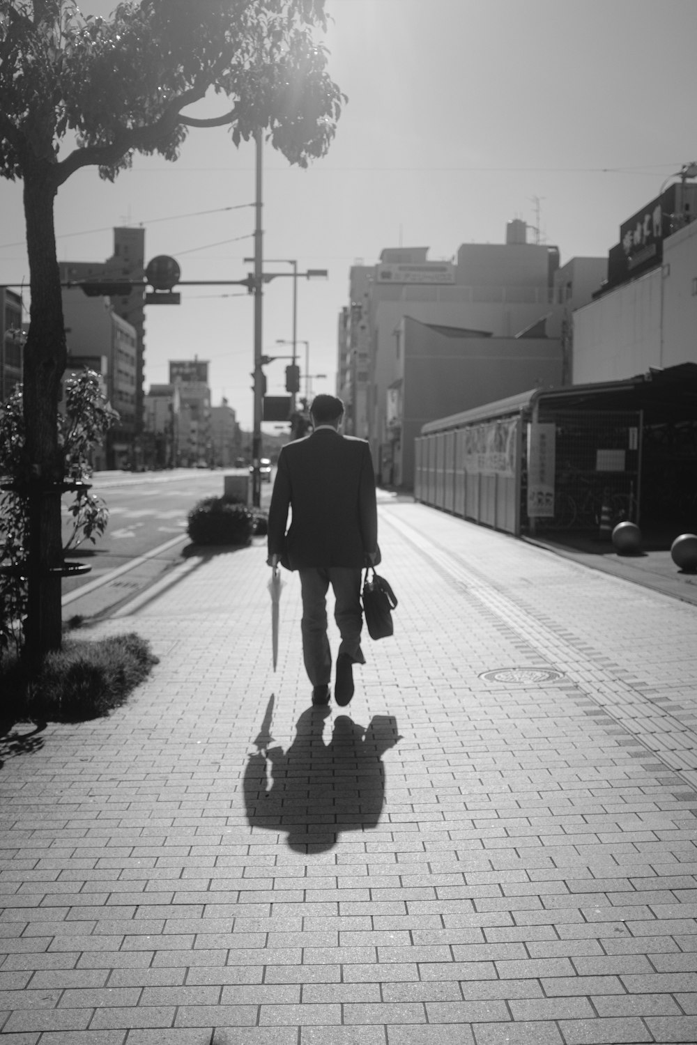 man in black coat walking on sidewalk during daytime