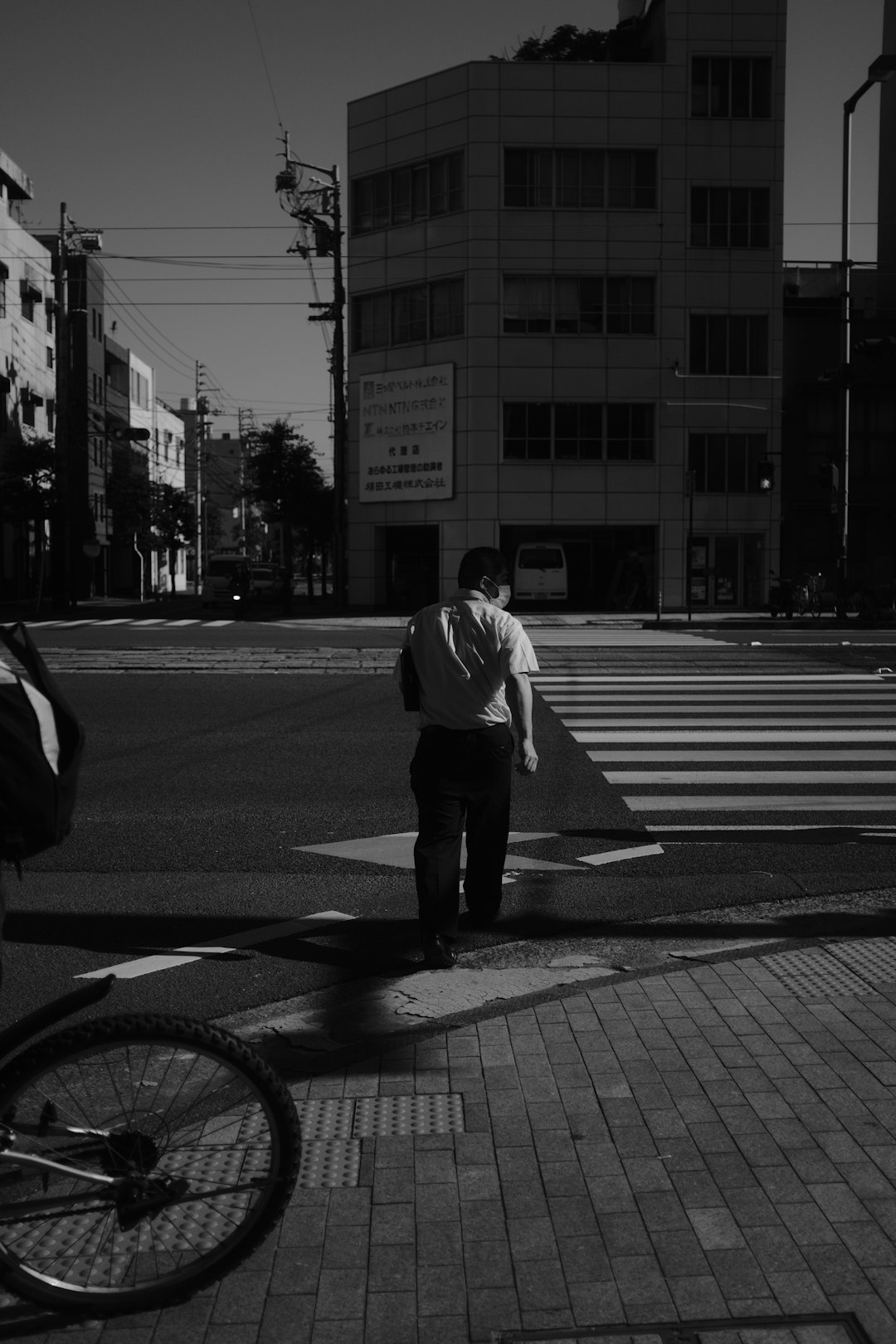 man in white dress shirt and black pants walking on pedestrian lane in grayscale photography