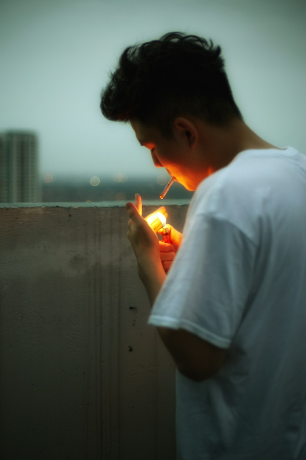 man in white t-shirt holding orange disposable lighter