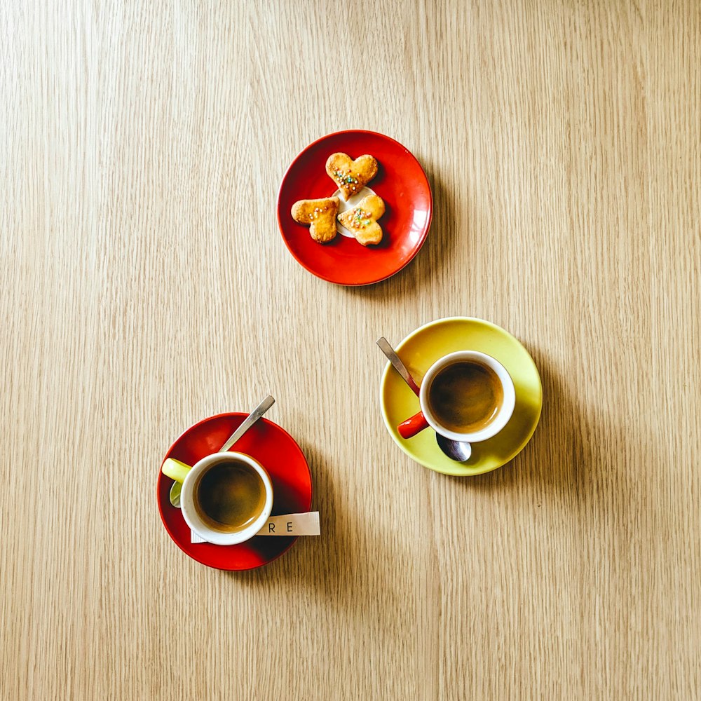 red and green ceramic mug on saucer beside green ceramic mug