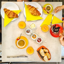 person holding bread and sausage on white ceramic plate