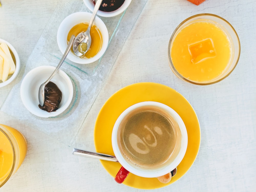 노란색 접시에 커피가 있는 흰색 세라믹 머그잔