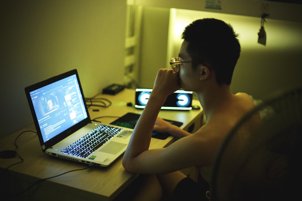 topless man sitting in front of laptop computer