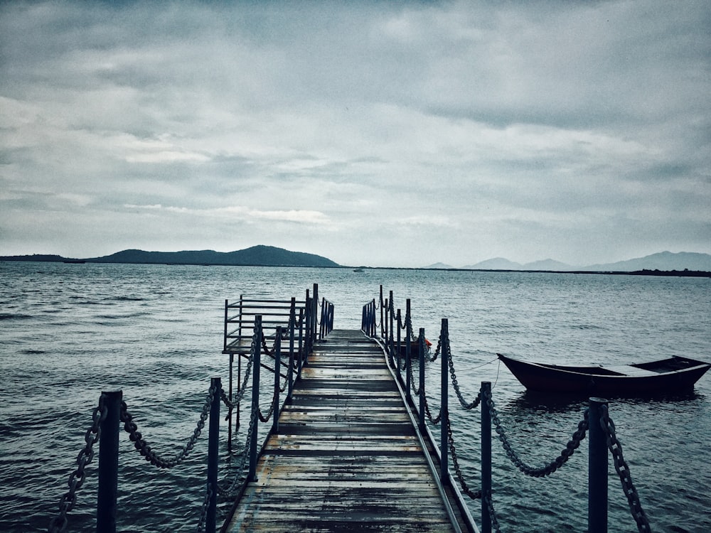 brown wooden dock on sea under white clouds during daytime