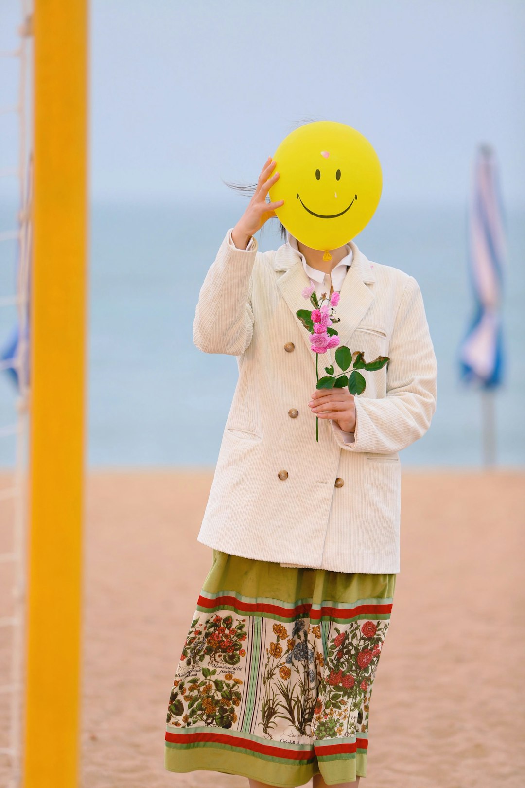 woman in white coat holding yellow balloon