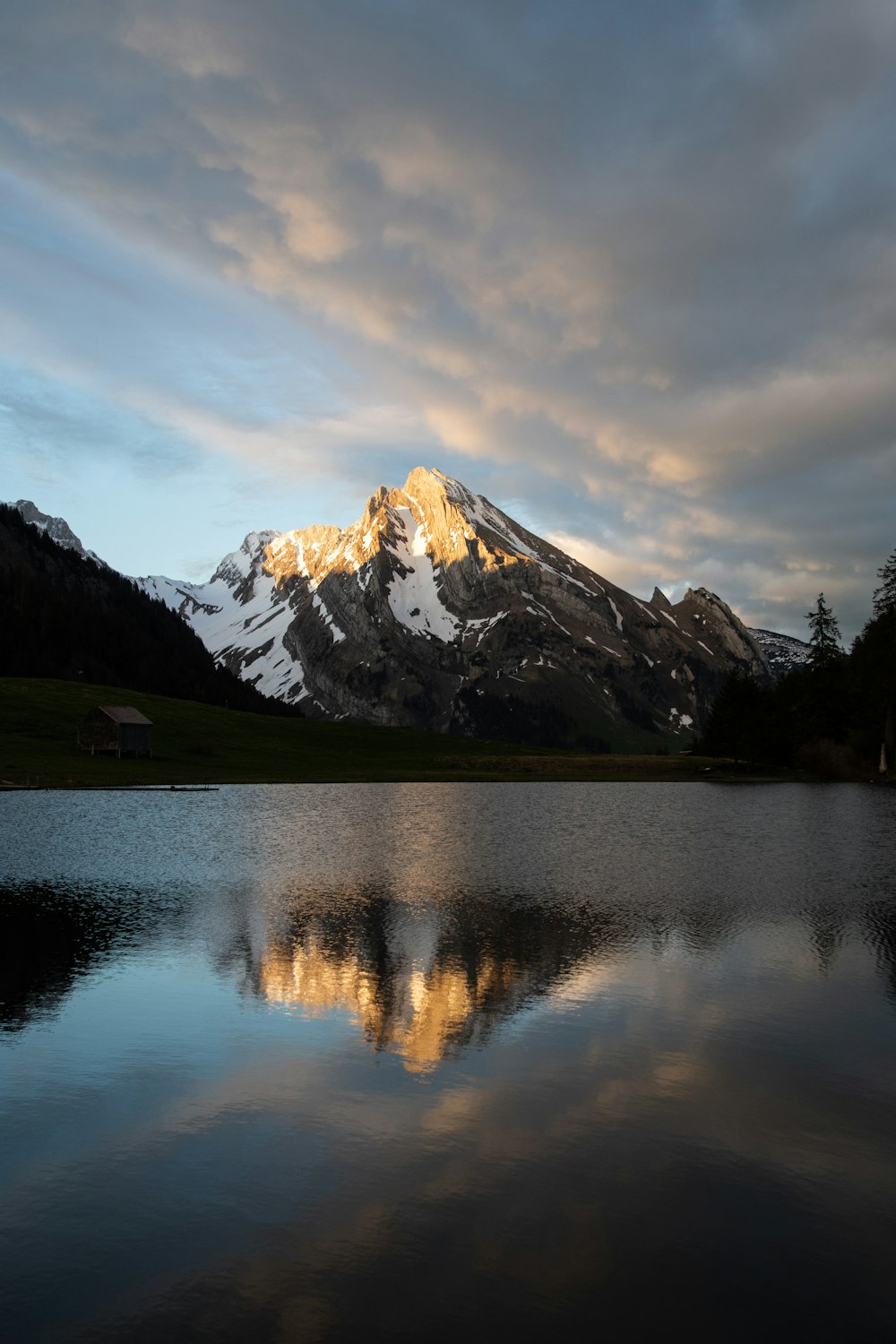 lago cerca de la montaña cubierta de nieve bajo el cielo nublado durante el día