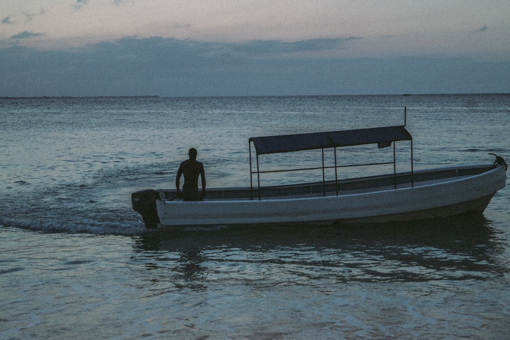 man and woman sitting on white and blue boat on sea during daytime