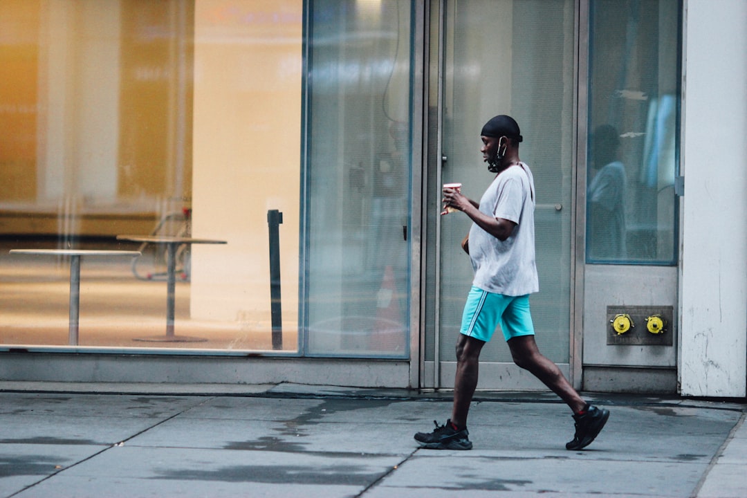 man in white shirt and blue shorts standing near glass door