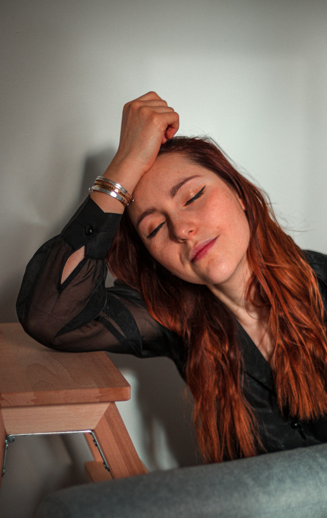 woman in black leather jacket leaning on brown wooden table