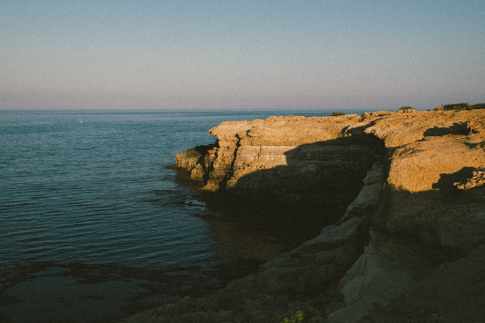 Montaña rocosa marrón junto al mar azul bajo el cielo azul durante el día