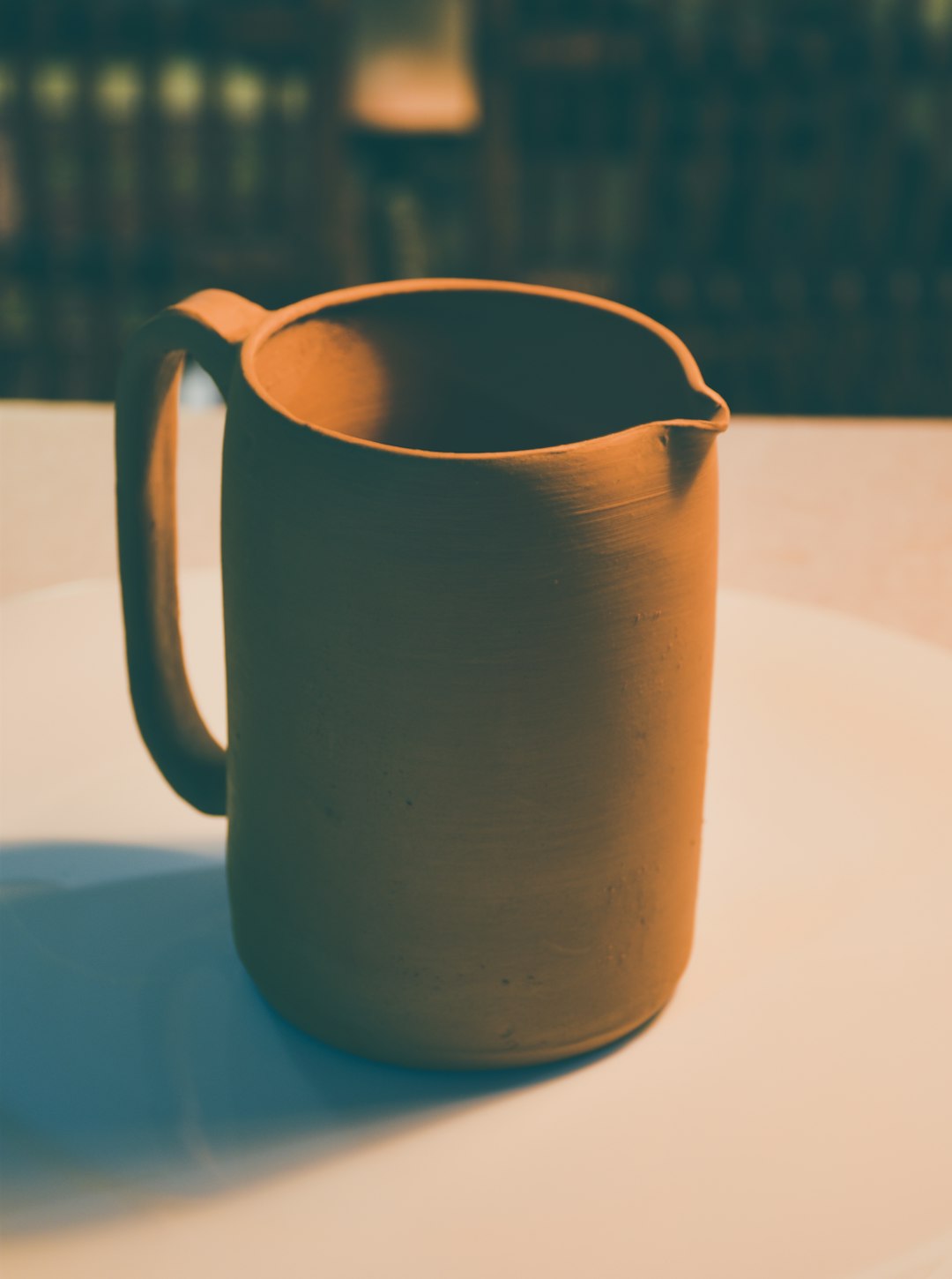 brown ceramic pitcher on blue table