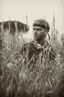 man in black and white plaid button up shirt standing on grass field