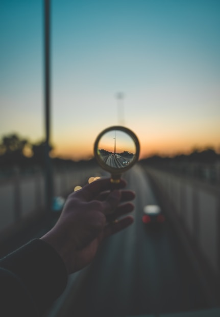 person holding magnifying glass during sunset