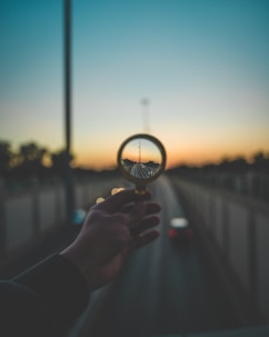 person holding magnifying glass during sunset