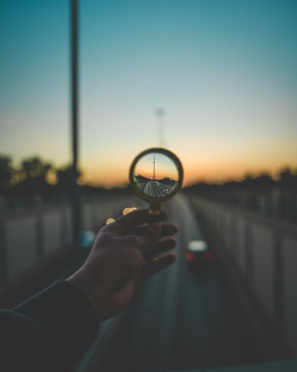 person holding magnifying glass during sunset