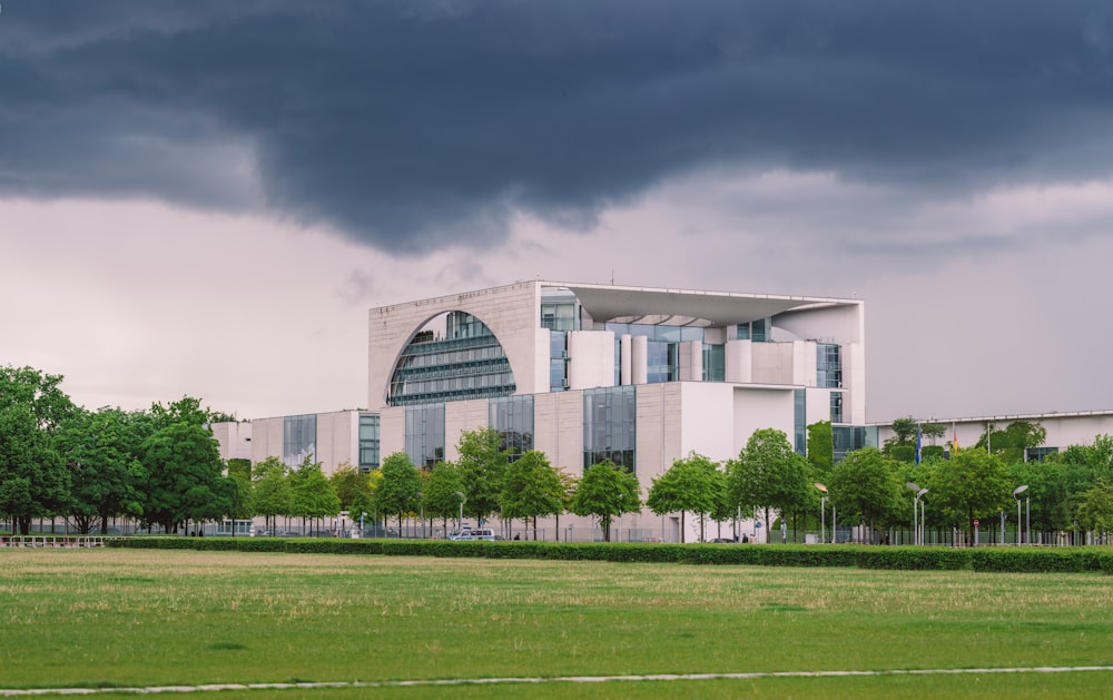 white concrete building near green grass field under gray sky