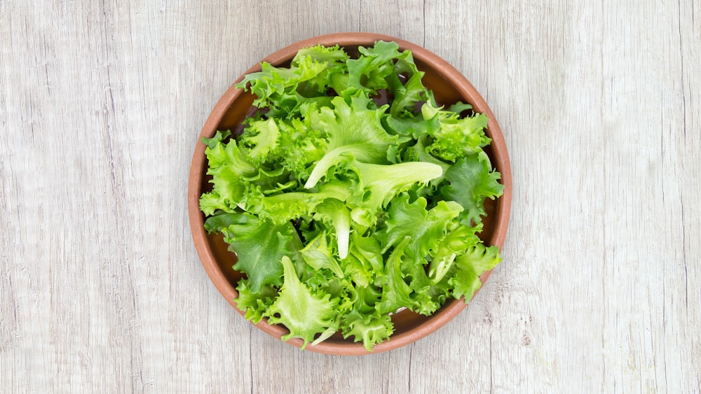 verdura verde su ciotola di plastica rotonda marrone