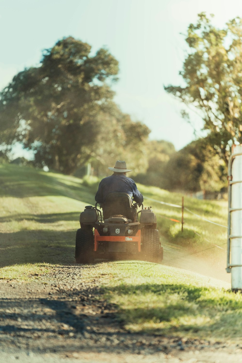 man riding red and black ride on lawn mower on green grass field during daytime