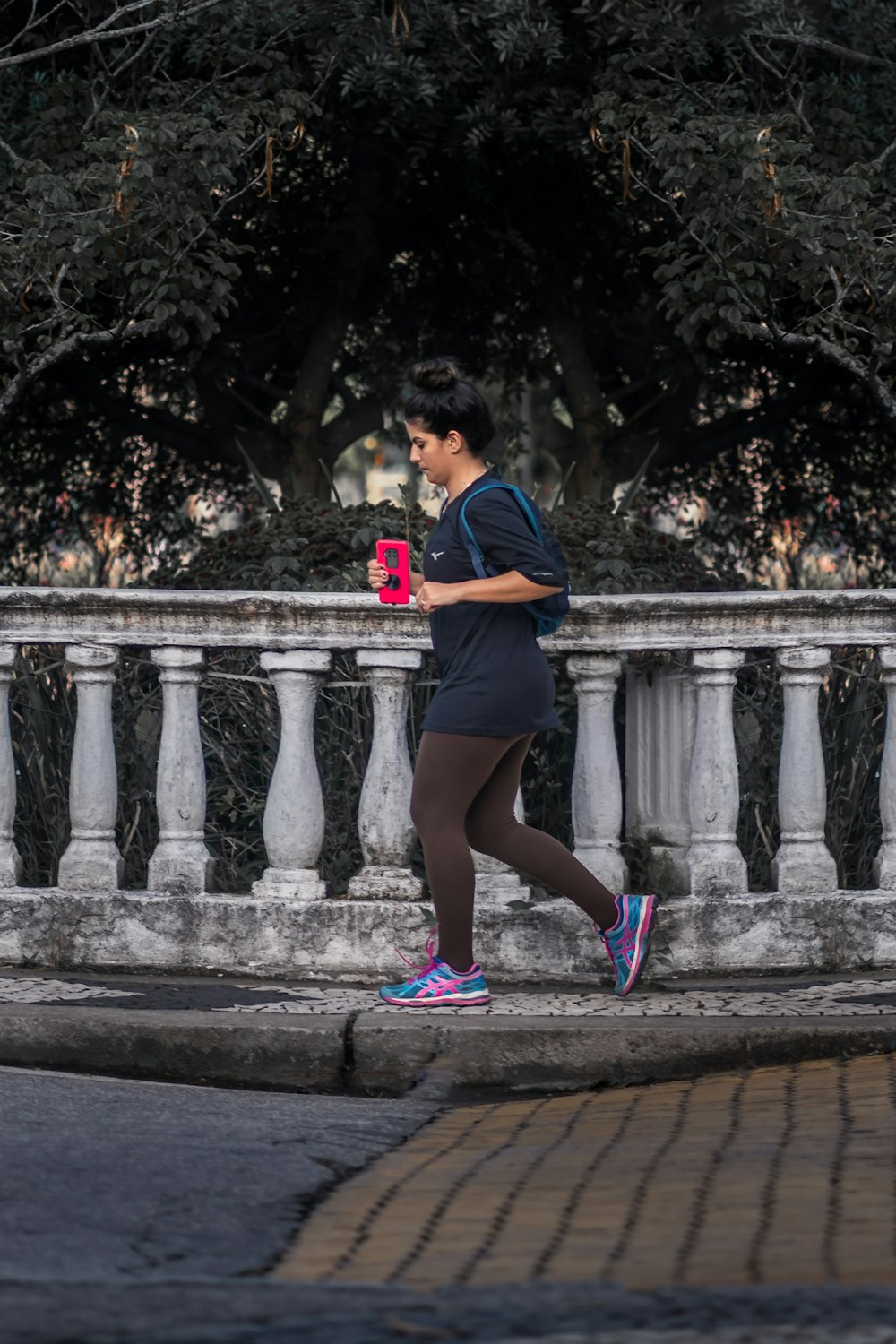 Mujer con camiseta azul y pantalones cortos negros de pie en un puente de hormigón durante el día