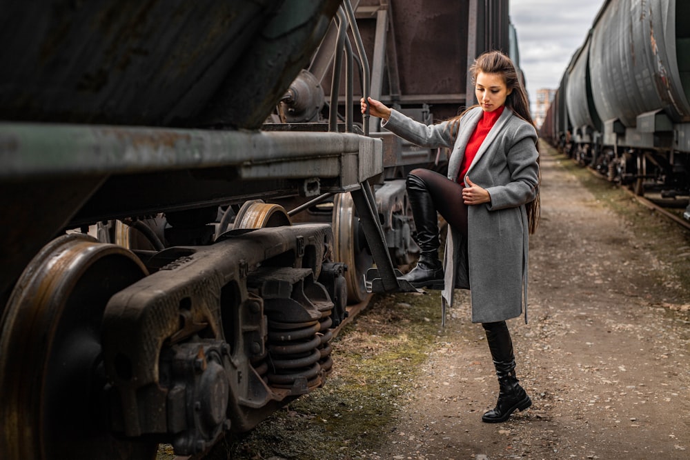 woman in gray coat standing beside train during daytime