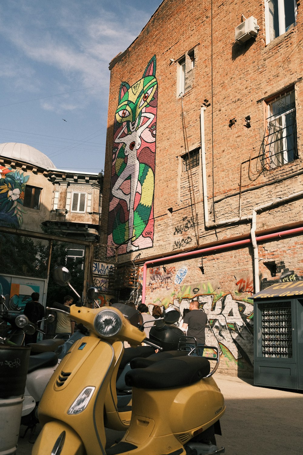 yellow and black motor scooter parked beside brown concrete building during daytime