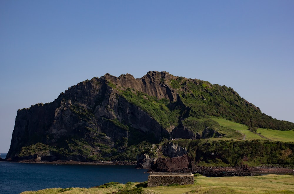 green and brown mountain beside body of water during daytime