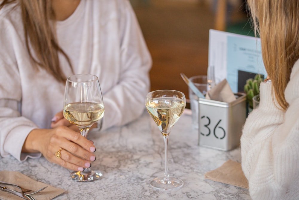 透明なワイングラスを持つ白い長袖シャツを着た女性