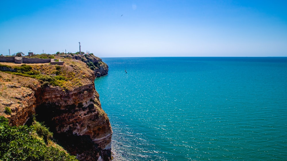 farol branco e preto no penhasco perto do corpo de água durante o dia