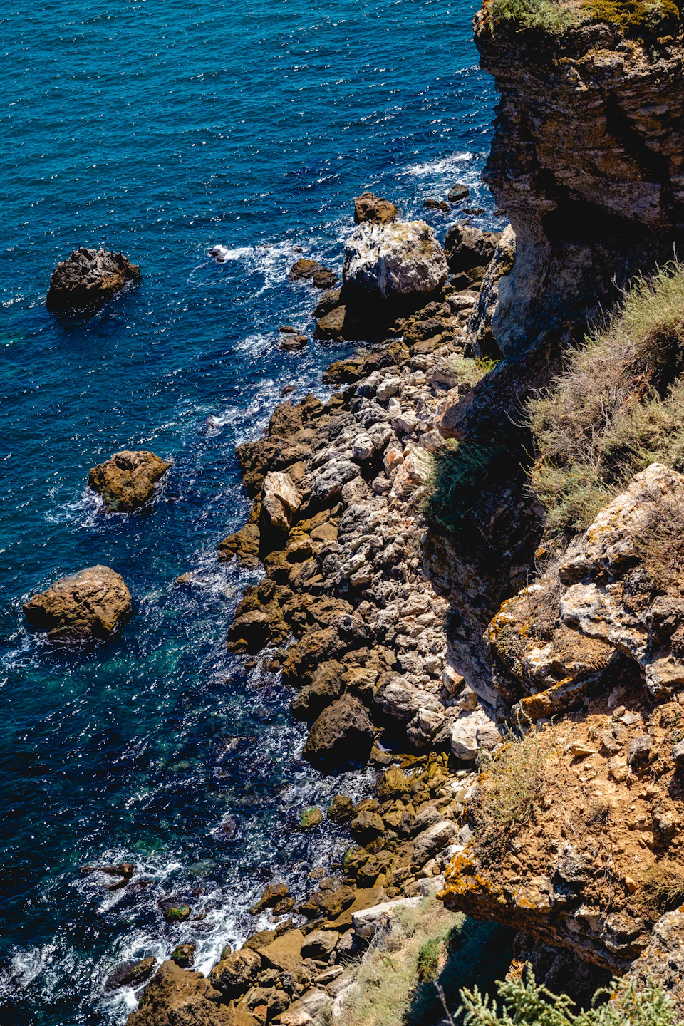 Rocky cliff overlooking the ocean with waves crashing against the rocky shoreline below