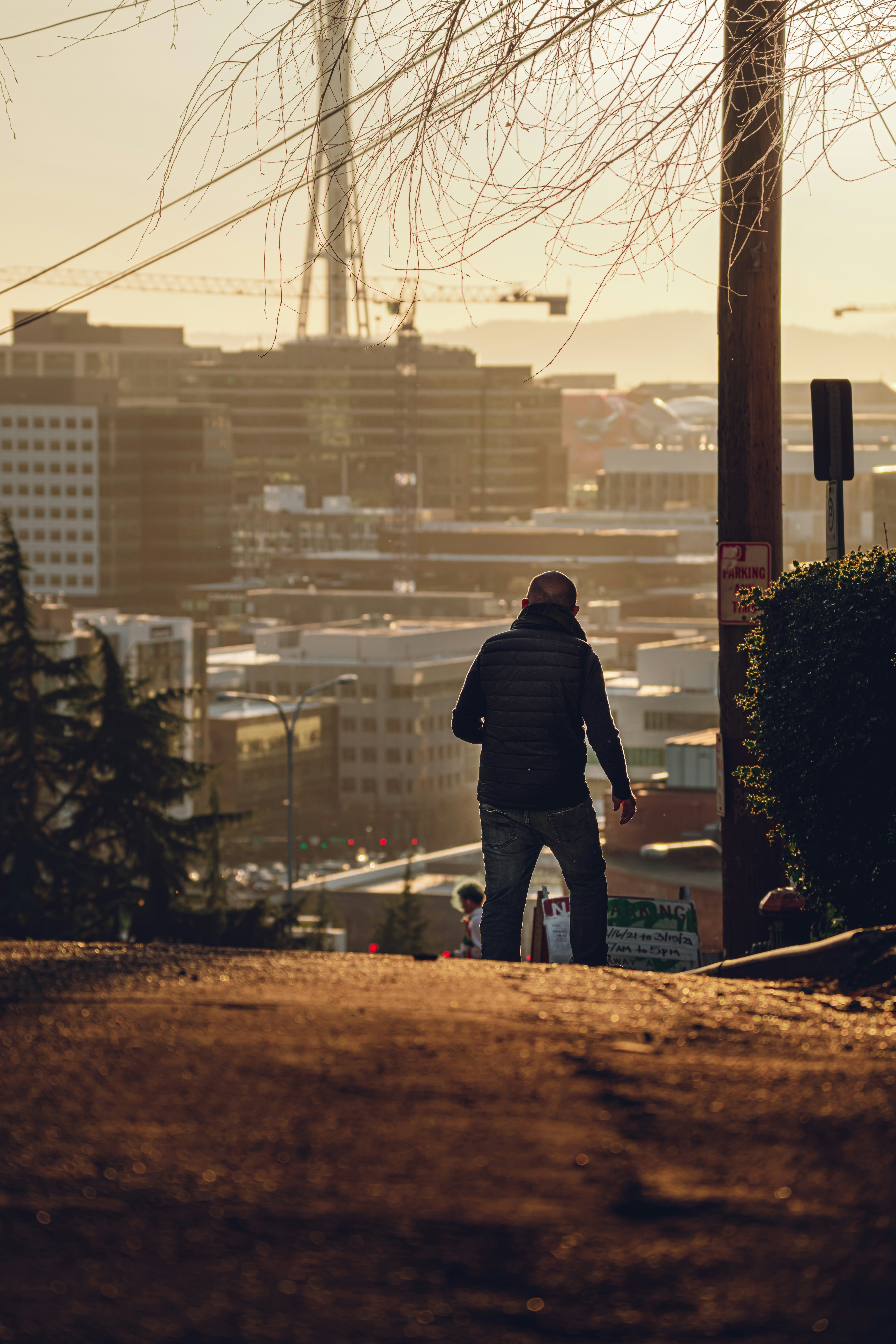 昼間、茶色の木製の柵の上に立つ黒いジャケットとブルーデニムのジーンズの男性