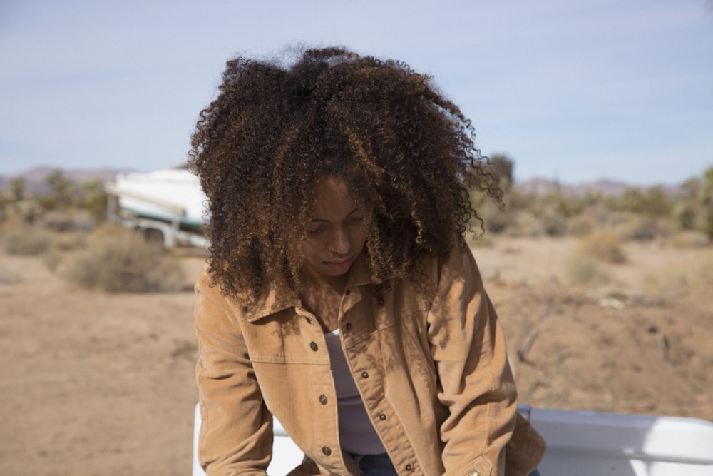 woman in brown jacket standing on beach during daytime