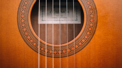 brown acoustic guitar on brown wooden surface