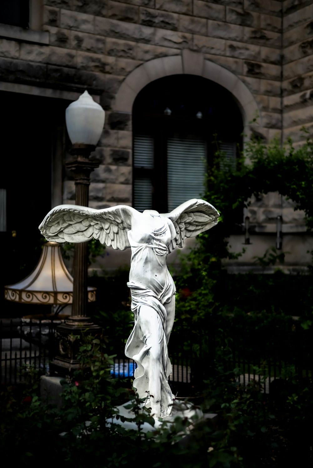 statue d’ange près de la clôture en métal noir pendant la journée