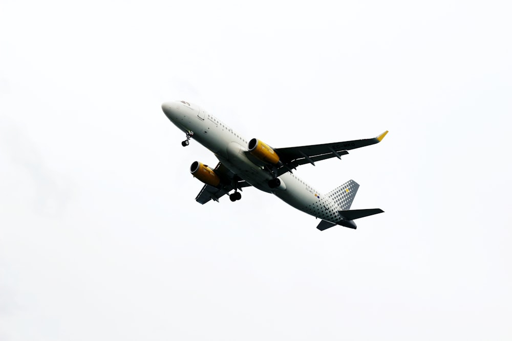 Avión blanco y amarillo volando durante el día