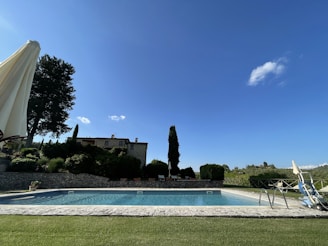 A serene outdoor pool surrounded by green grass and trees.